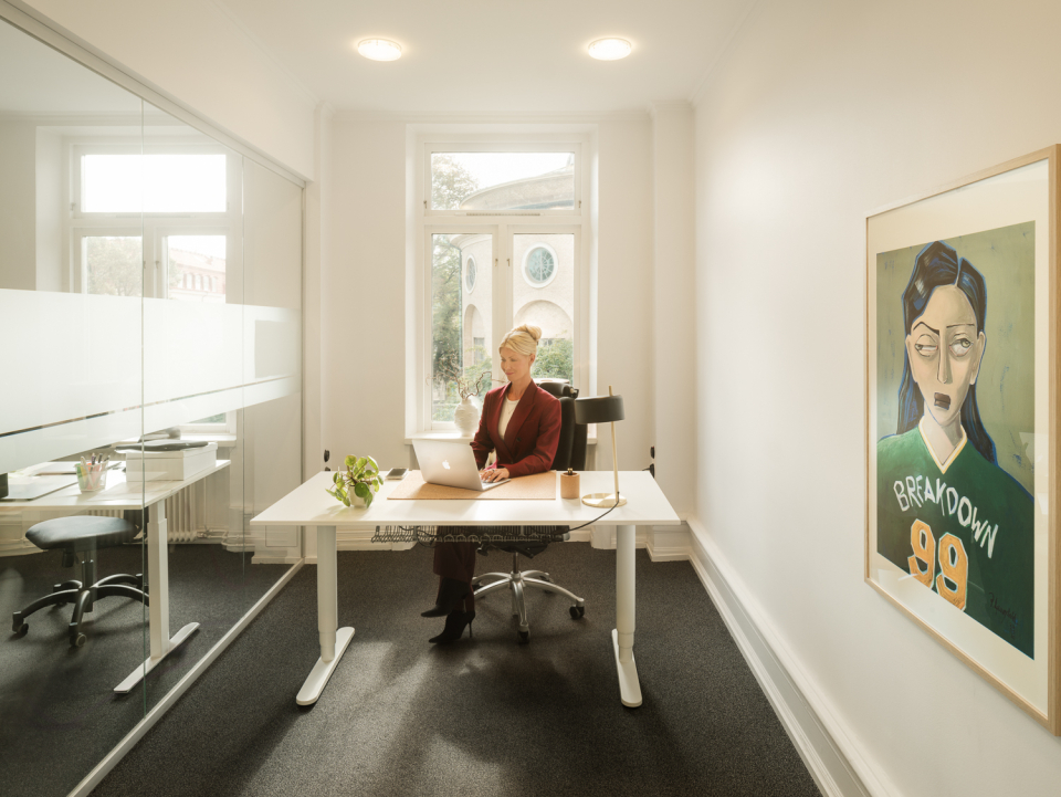 Person sitter vid ett skrivbord på ett ljust kontor.